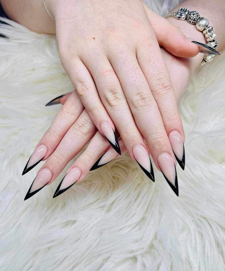 Long stiletto nails with a nude base and black French tips